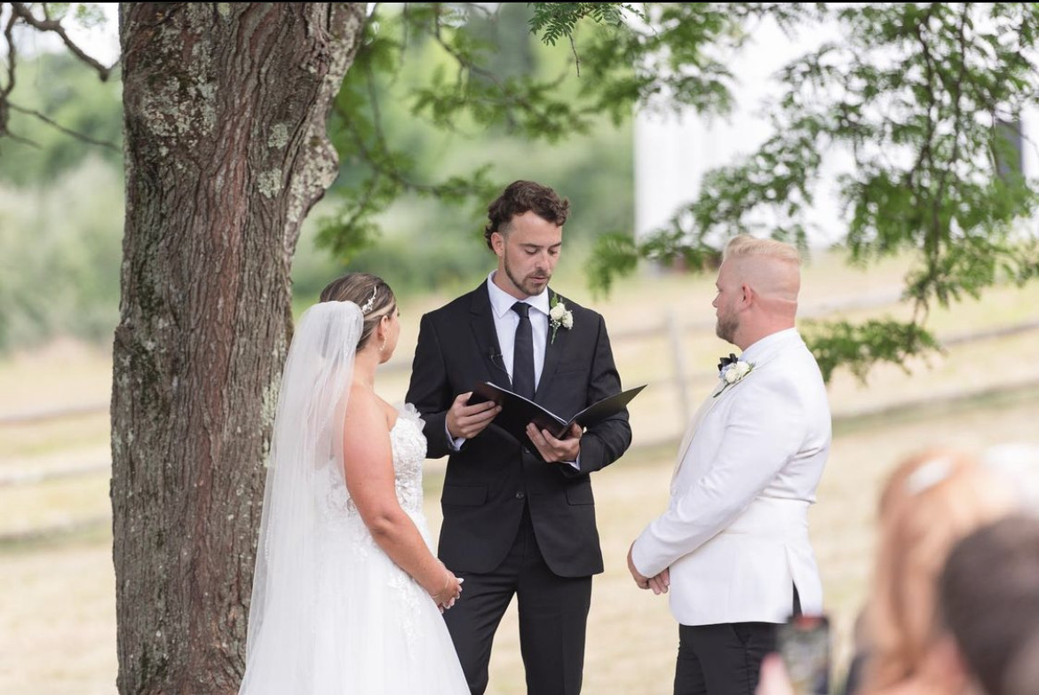 Shane officiating an outdoor wedding ceremony under a tree